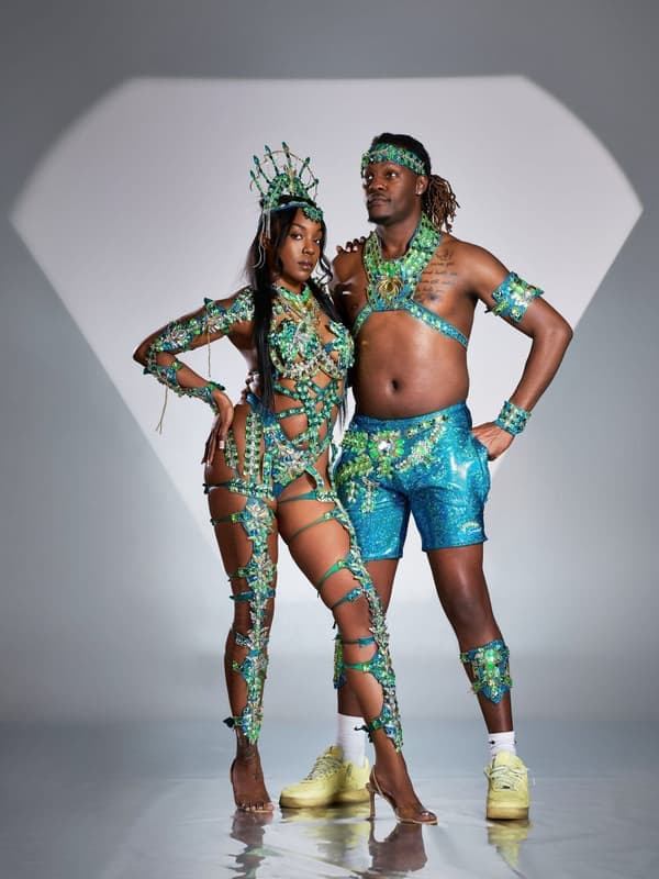 A man and a woman in matching turquoise and silver costumes posing in a studio