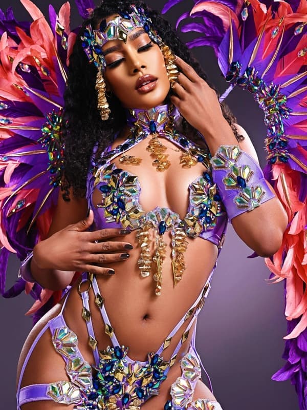 Model in a purple and blue jewelled costume with a large feathered collar