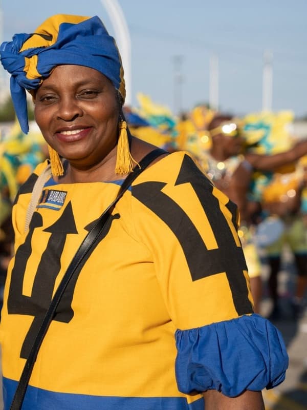 A smiling woman in a yellow and blue costume at a carnival road event