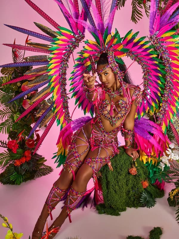 Model in a pink and gold costume with a large feathered halo among yellow flowers