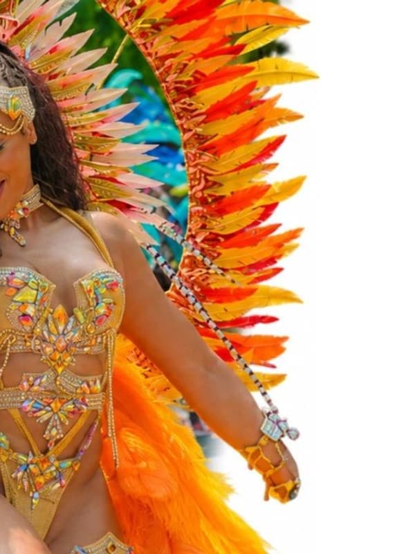 A masquerader in an orange and gold feathered costume on the road
